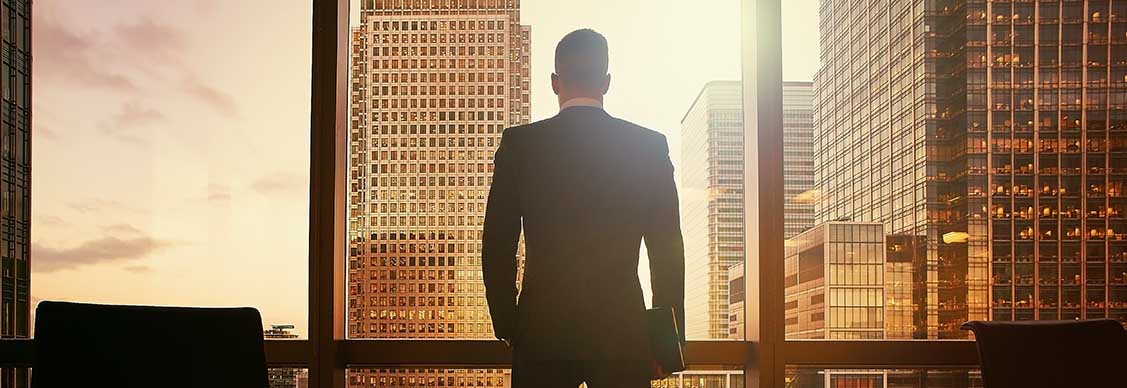 オフィスビルを眺めながら投資戦略を思案する外資系投資家のイメージ