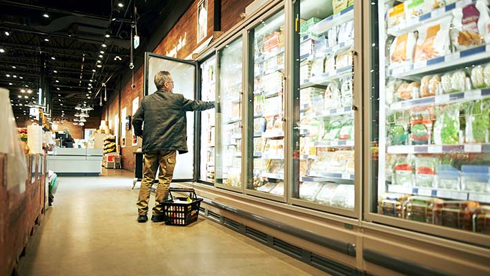 A man picking out stuff from vending machine and keeping it in a basket