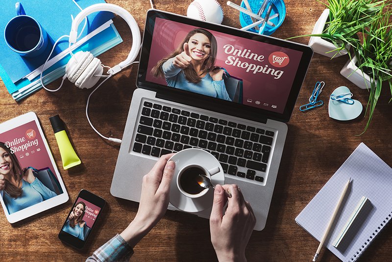 オンラインショッピングのウェブサイト、ノートパソコンの画面、コーヒーを持つ女性の手