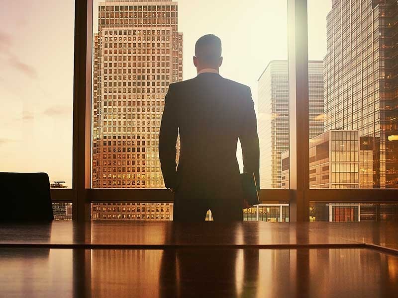 オフィスビルを眺めながら投資戦略を思案する外資系投資家のイメージ