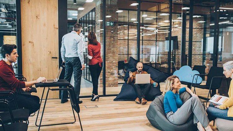 A group of employees work together in a modern workplace lounge area