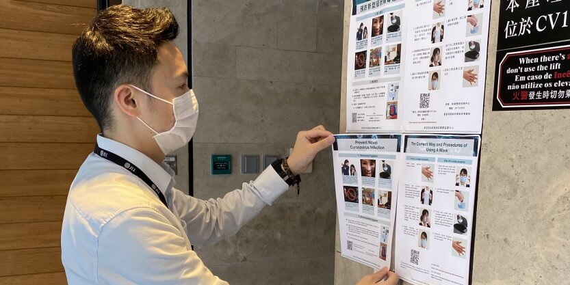 A JLL employee sticking a poster on the wall written prevention of corona virus