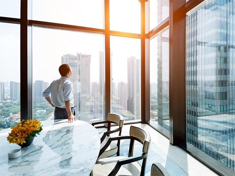 Man looks out of window at buildings