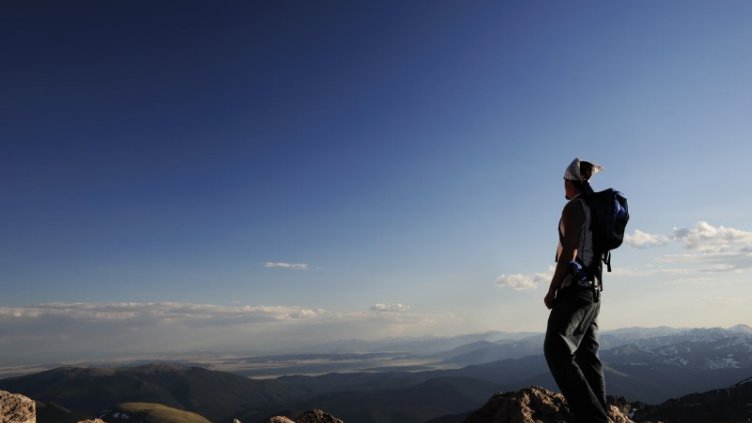 Man stands alone on top of a mountain